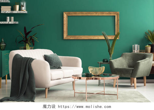 绿色起居室内的米色沙发和扶手椅之间的铜桌
